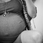 a pregnant woman sitting on a chair holding a cell phone to her ear